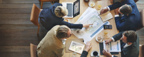 Business leaders discuss strategy around a meeting table.